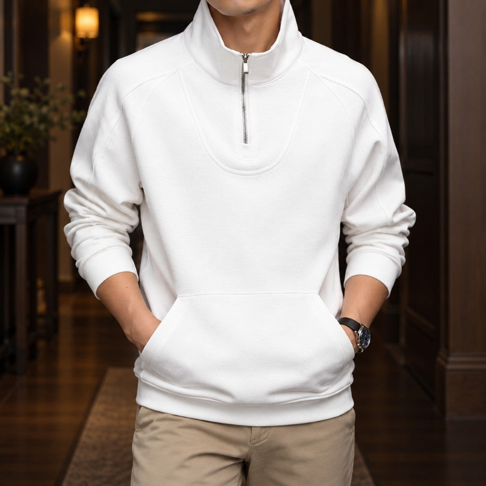 Man wearing a cream fleece quarter-zip pullover with raglan sleeves, a front pouch pocket, and tan pants.
