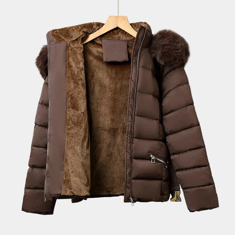 Brown puffer jacket with an open zipper, plush brown lining, a hood, and faux fur pom-poms on a hanger.