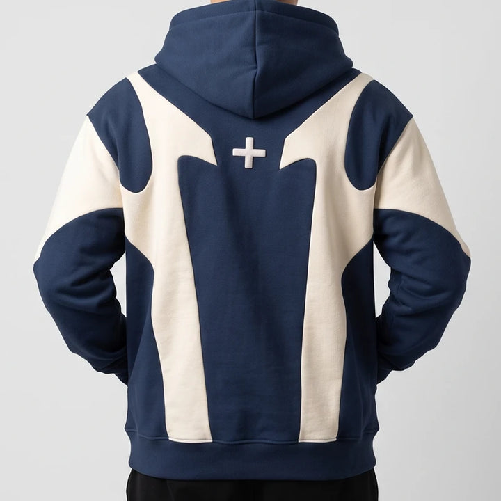 Man wearing a navy blue and cream colorblocked hoodie featuring a small white plus symbol on the back.