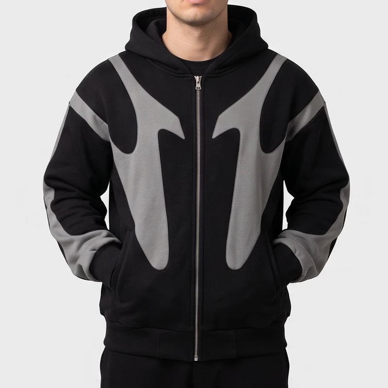 Man wearing a black full-zip hoodie featuring contrasting grey curved paneling across the chest and sleeves.
