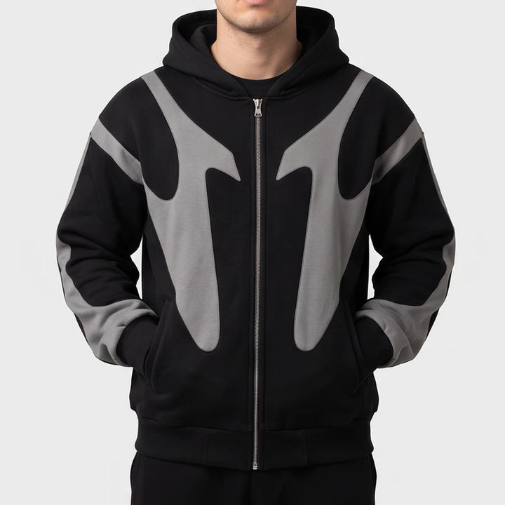 Man wearing a black full-zip hoodie featuring contrasting grey curved paneling across the chest and sleeves.