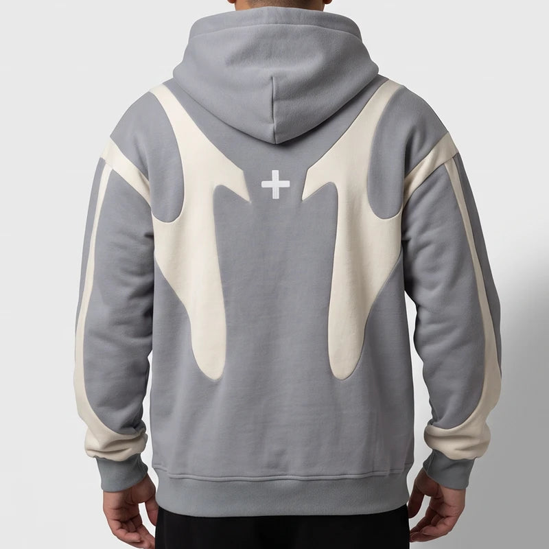 Man wearing a grey pullover hoodie with cream curved accents on the back and sleeves against a white background.