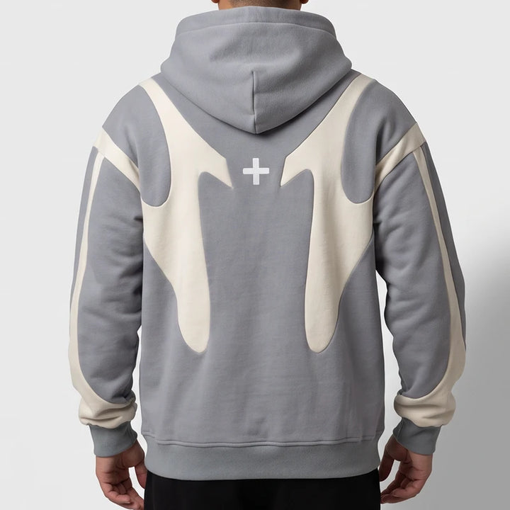 Man wearing a grey pullover hoodie with cream curved accents on the back and sleeves against a white background.
