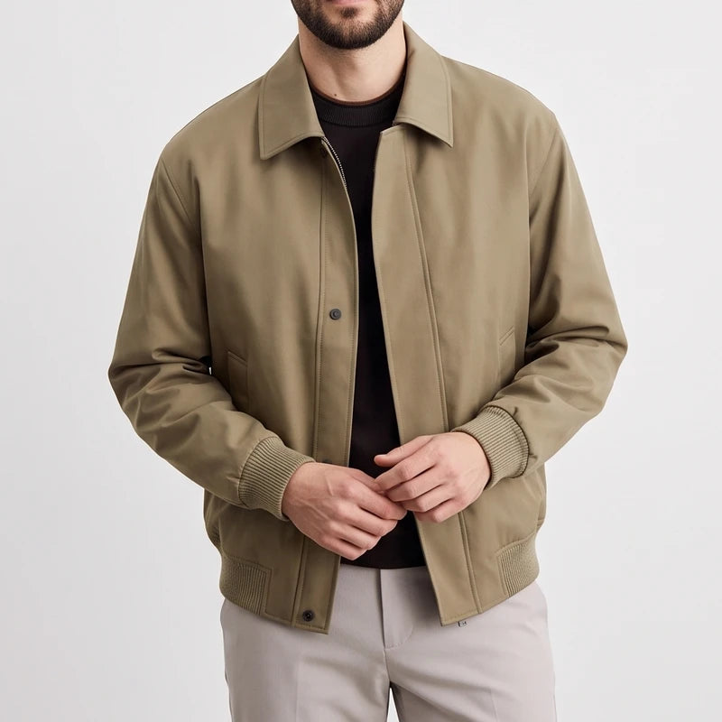 Man wearing an open light olive green bomber jacket with rib-knit cuffs and hem, over a dark shirt.