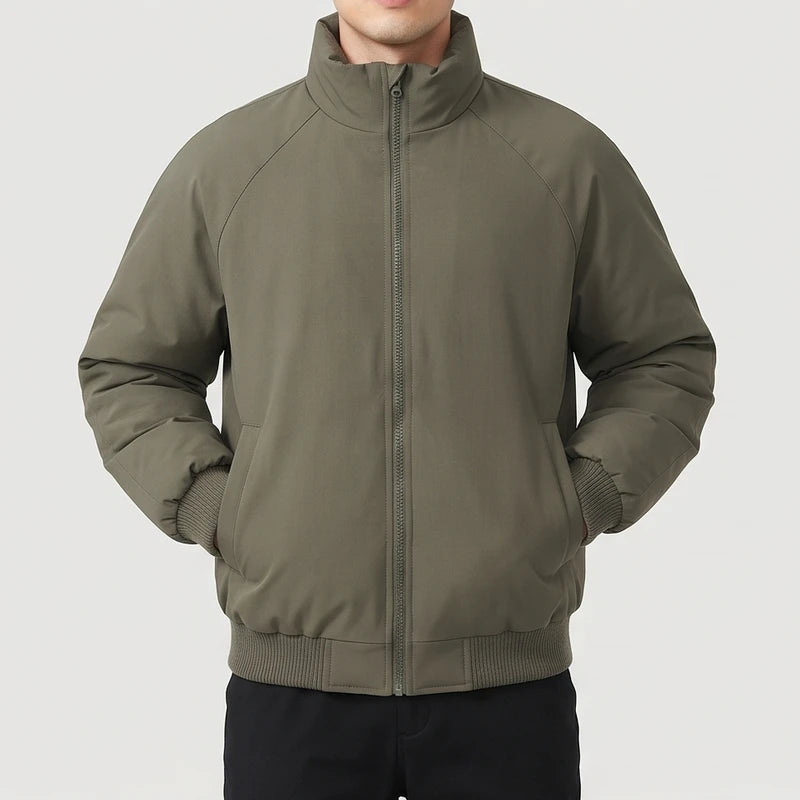 Man wearing a dark olive green bomber jacket with raglan sleeves, ribbed cuffs and hem, and a fully zipped stand collar.