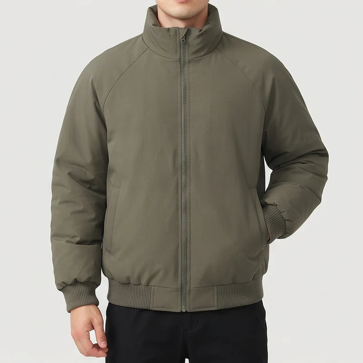Man wearing a puffy olive green bomber jacket with a stand collar, front zipper, and ribbed cuffs and hem.