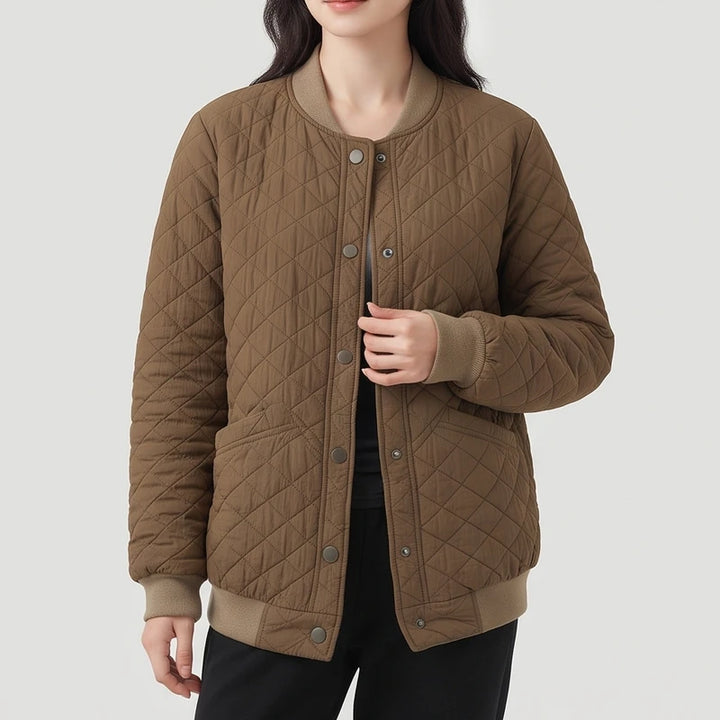 Woman wearing a brown quilted bomber jacket with snap buttons, ribbed cuffs, collar, and hem, and two front pockets.