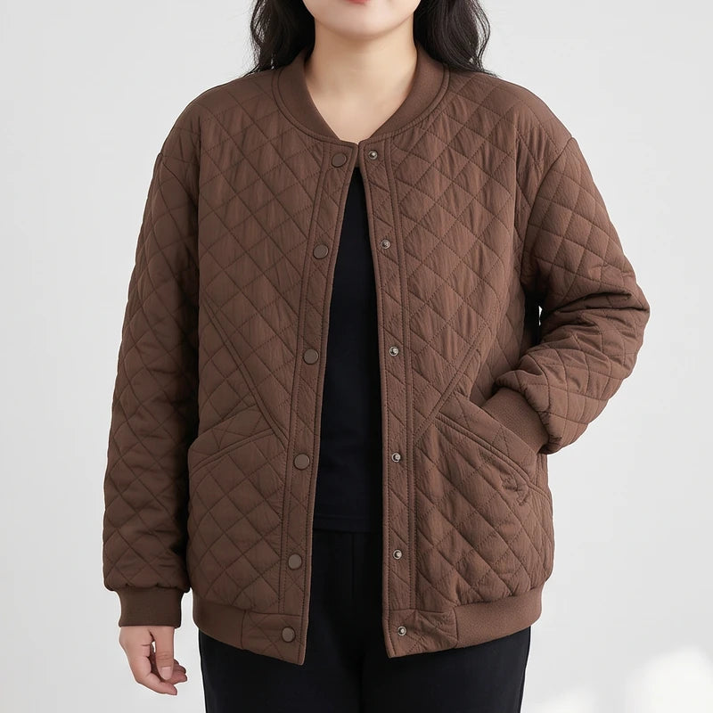 Woman wearing a brown quilted bomber jacket with a ribbed collar, snap buttons, and side pockets, standing against a white background.