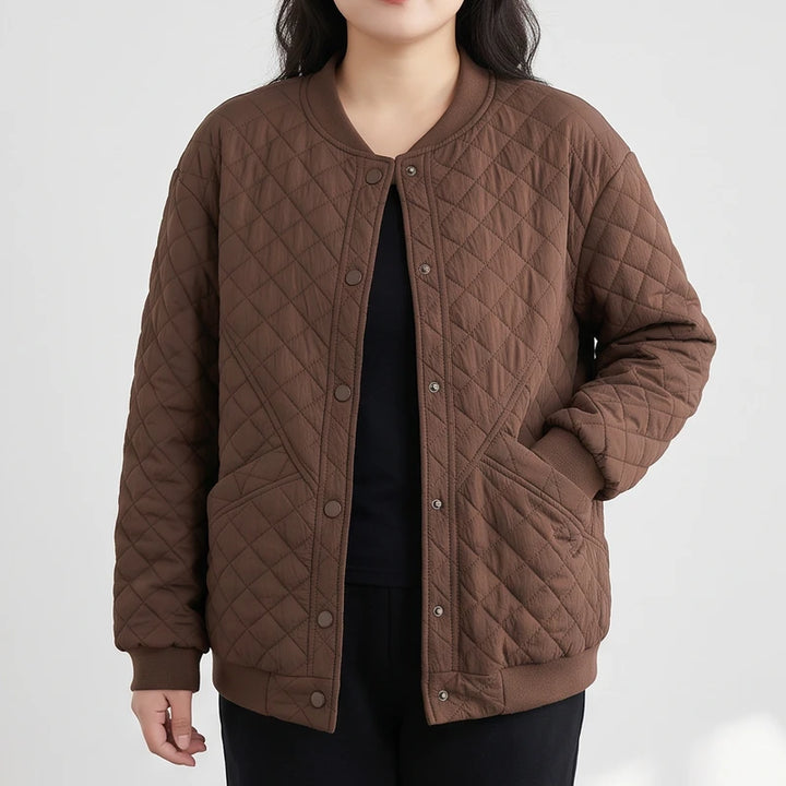 Woman wearing a brown quilted bomber jacket with a ribbed collar, snap buttons, and side pockets, standing against a white background.