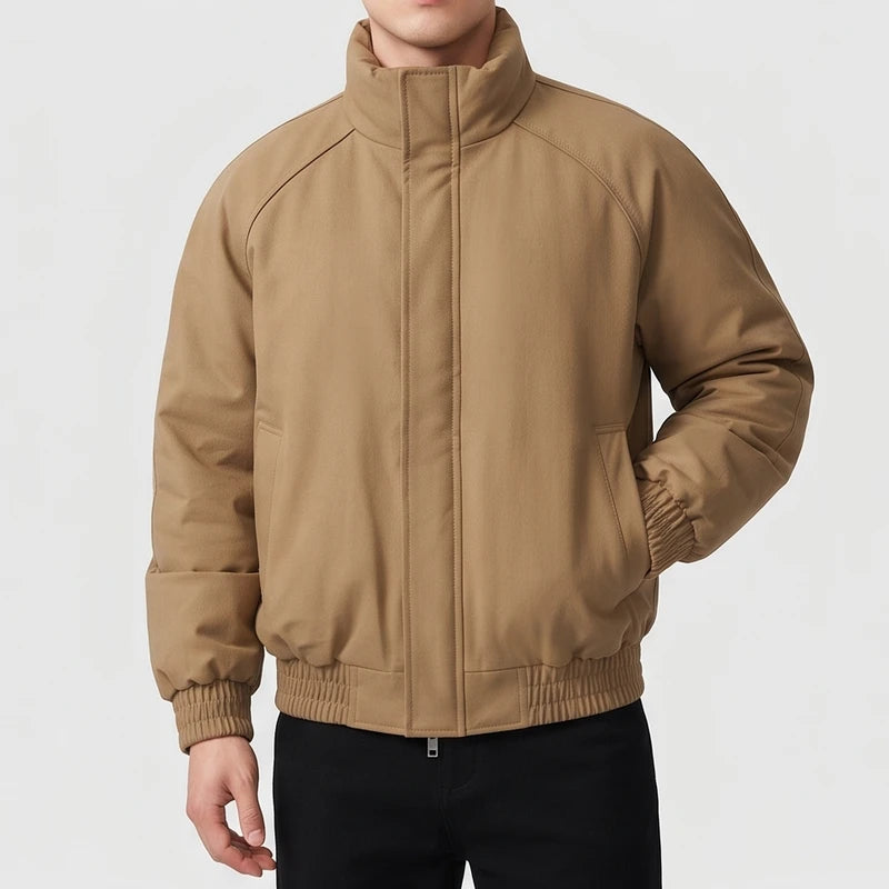 Man wearing a camel brown bomber jacket with a stand collar, ribbed cuffs, and hem, hands in pockets.