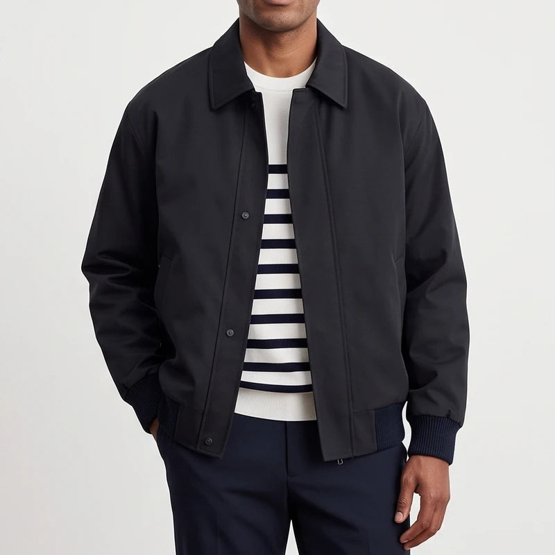 Man wearing a dark navy casual jacket with a collar, over a white and navy striped sweater and dark pants.
