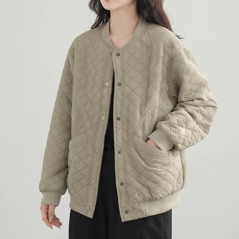 Woman wearing a relaxed-fit, light beige quilted bomber jacket with a ribbed collar, cuffs, and hem, and snap closures.