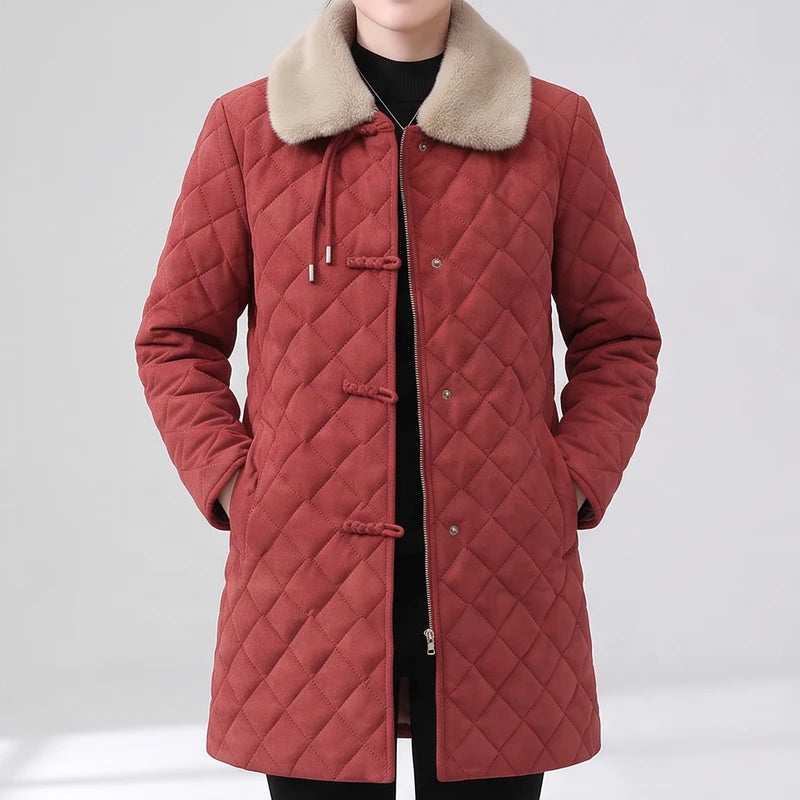 Woman wearing a long, red quilted jacket with a beige faux fur collar, hands in pockets.