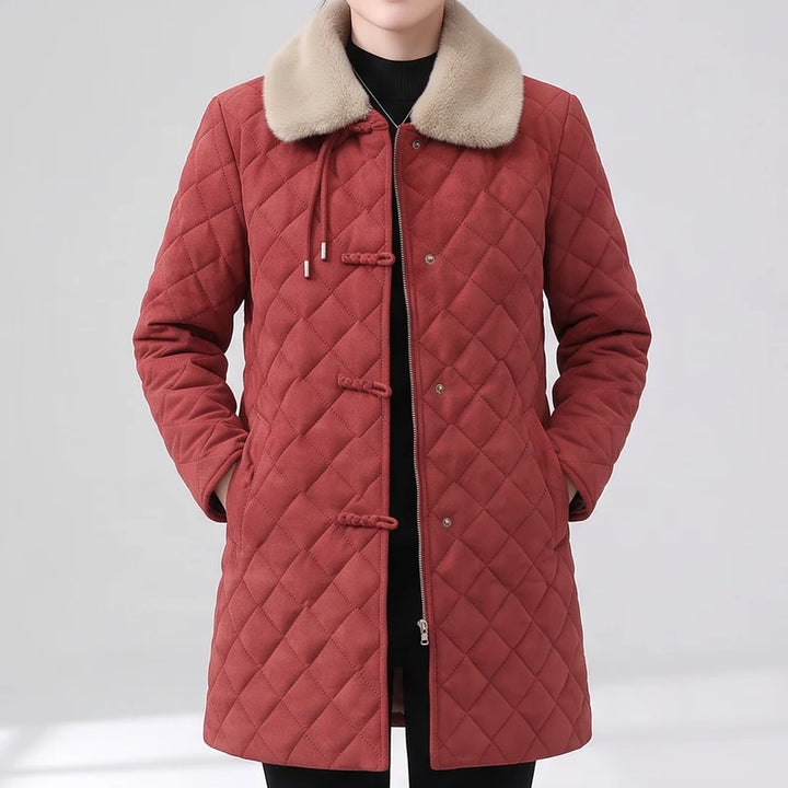 Woman wearing a long, red quilted jacket with a beige faux fur collar, hands in pockets.