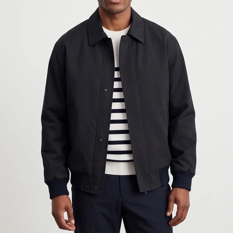 Man wearing a black collared jacket with snap buttons over a white and navy striped sweater, against a white background.