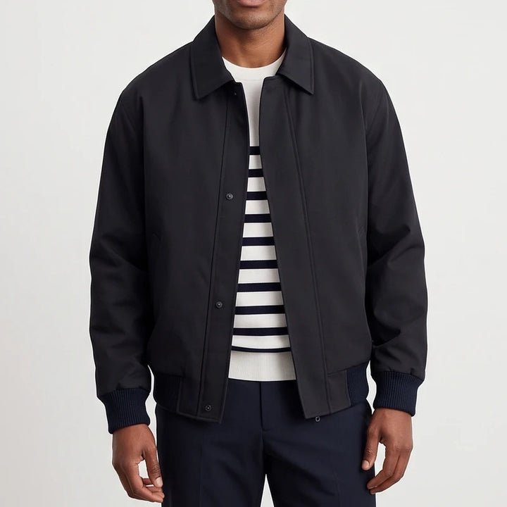 Man wearing a black collared jacket with snap buttons over a white and navy striped sweater, against a white background.