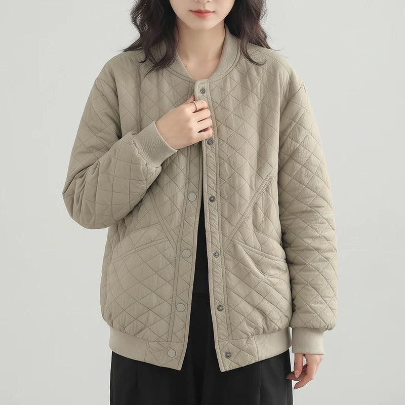 Woman wearing a light beige quilted bomber jacket with a ribbed collar, cuffs, and hem, standing against a light background.