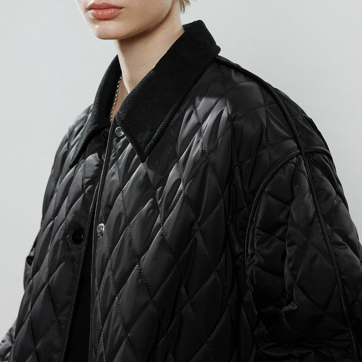 Close-up of a model wearing a black quilted jacket with a corduroy collar and snap buttons.