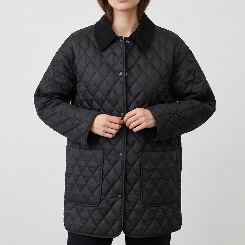 Woman wearing a black quilted jacket with a corduroy collar, front pockets, and snap buttons, hands near the closure.