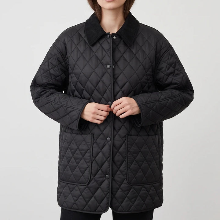 Woman wearing a black quilted jacket with a corduroy collar, front pockets, and snap buttons, hands near the closure.