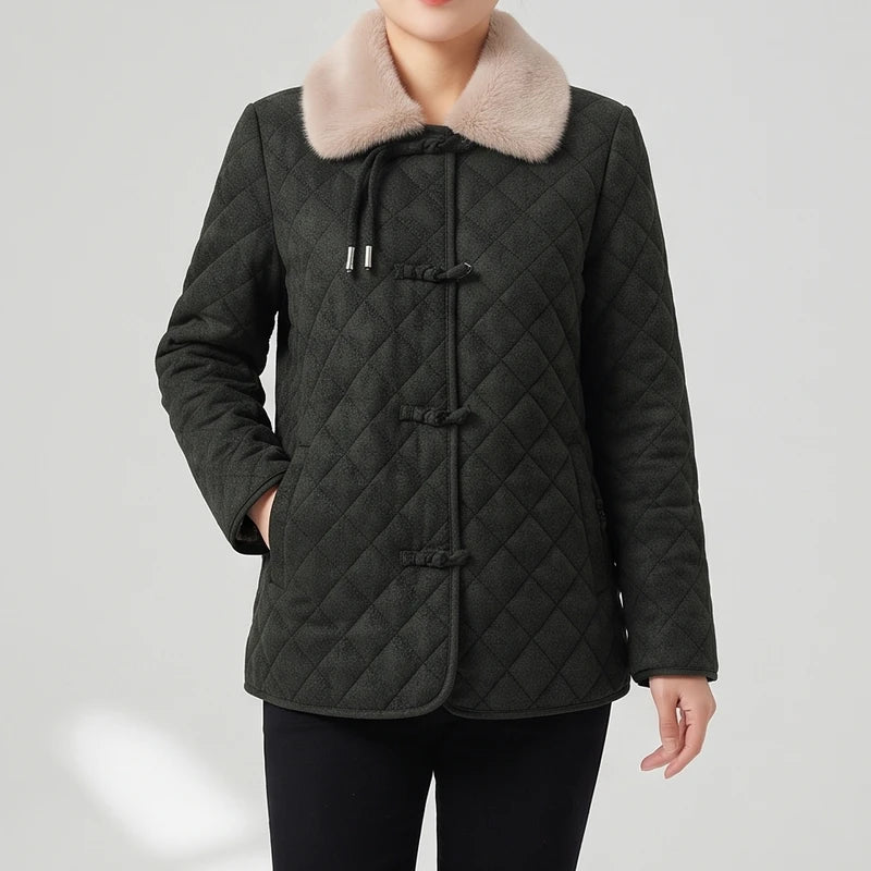 Woman wearing a quilted dark green jacket with a light pink faux fur collar and toggle button closures.