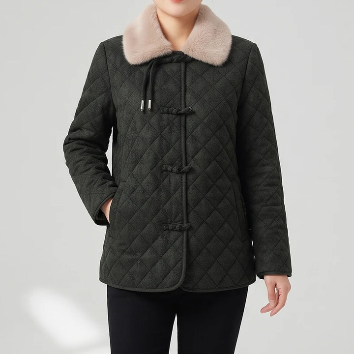 Woman wearing a quilted dark green jacket with a light pink faux fur collar and toggle button closures.
