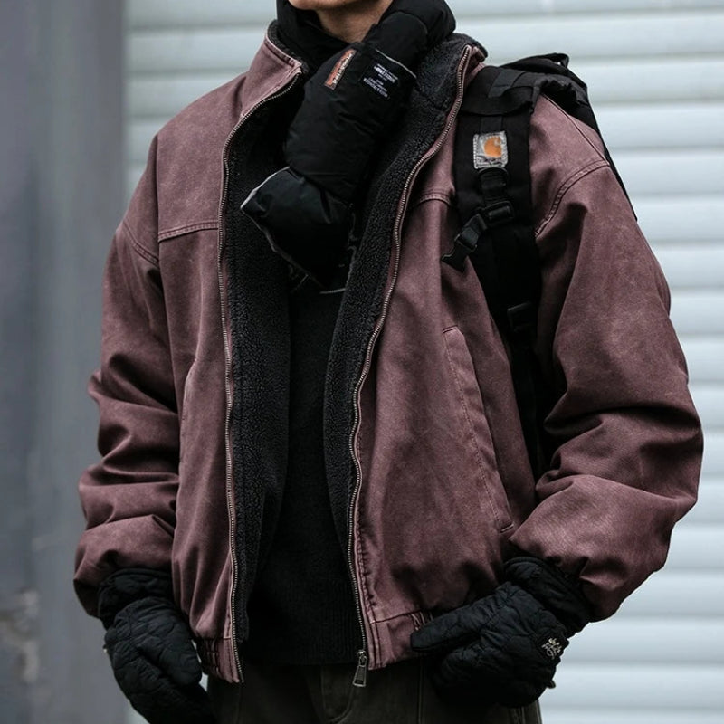 Man wearing a faded brown zip-up canvas jacket with black fleece lining, paired with winter gloves and a backpack.