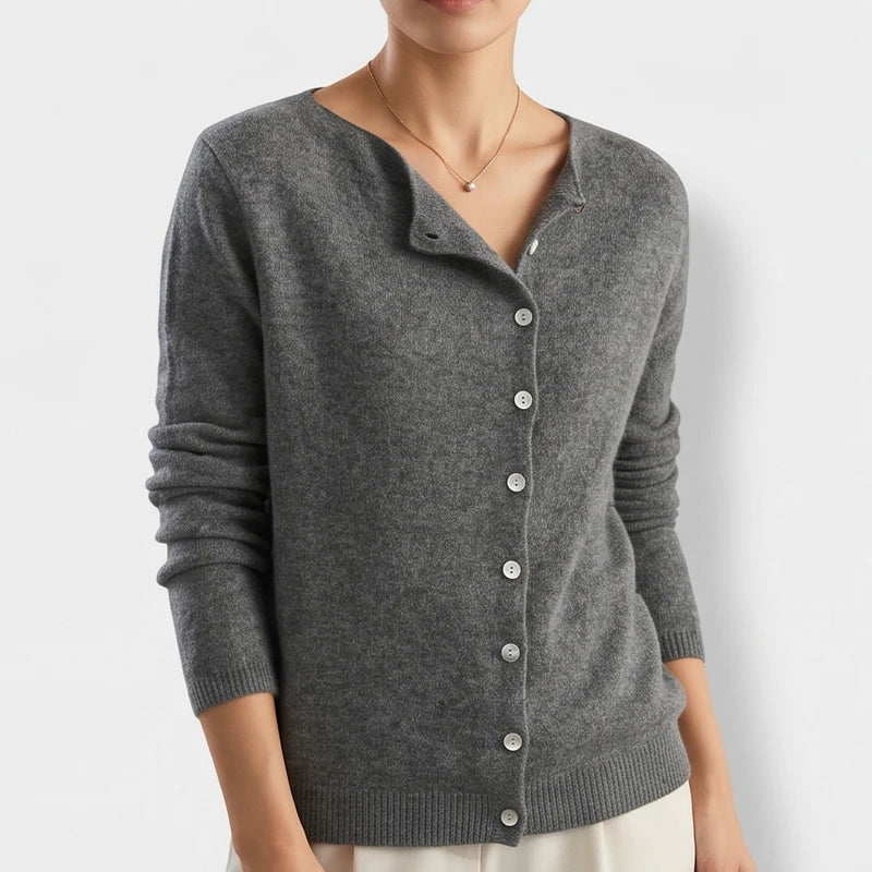 Woman wearing a dark gray knit cardigan with a rounded neckline and nine white buttons down the front.