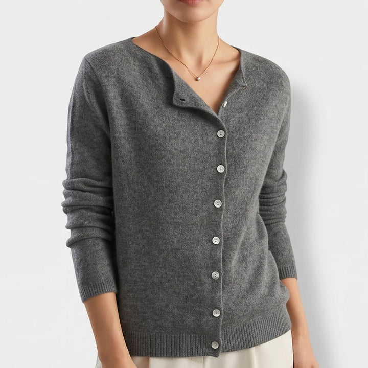 Woman wearing a dark gray knit cardigan with a rounded neckline and nine white buttons down the front.