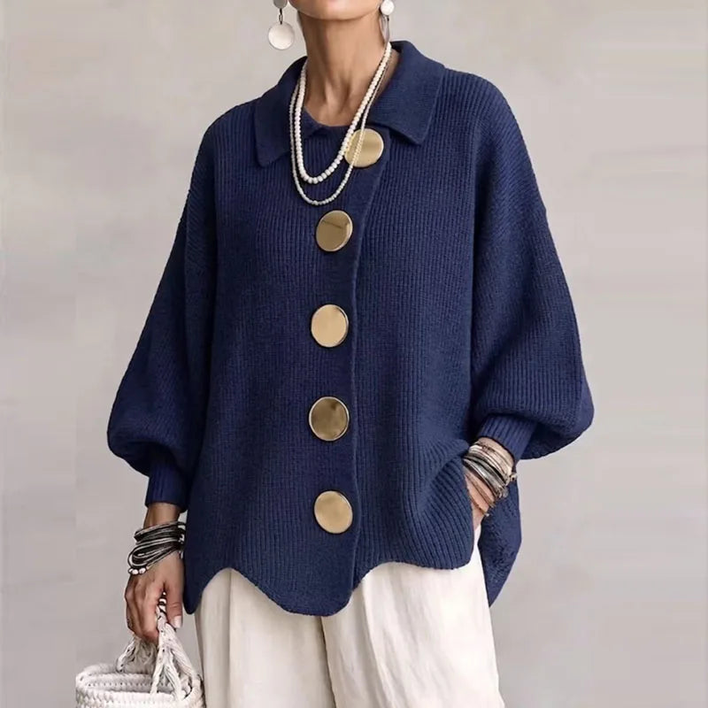 Woman wearing a navy blue button-front cardigan with large gold buttons, oversized sleeves, and a wavy hem.