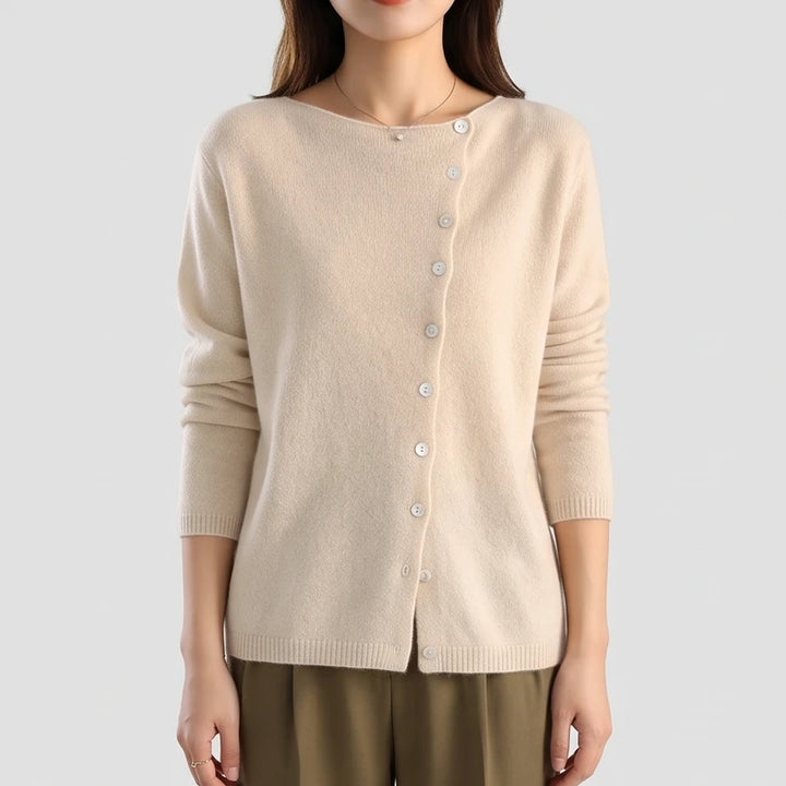 Woman wearing a beige knit cardigan with a boat neck and an off-center diagonal button placket.