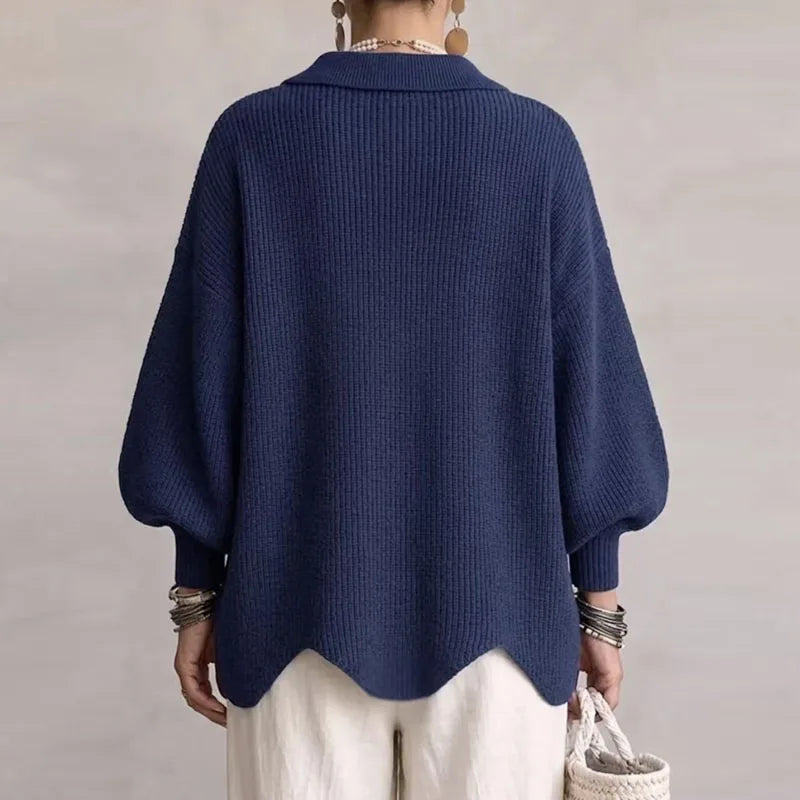 Woman wearing a navy blue ribbed knit cardigan with puffed sleeves and a unique scalloped hem, seen from the back.