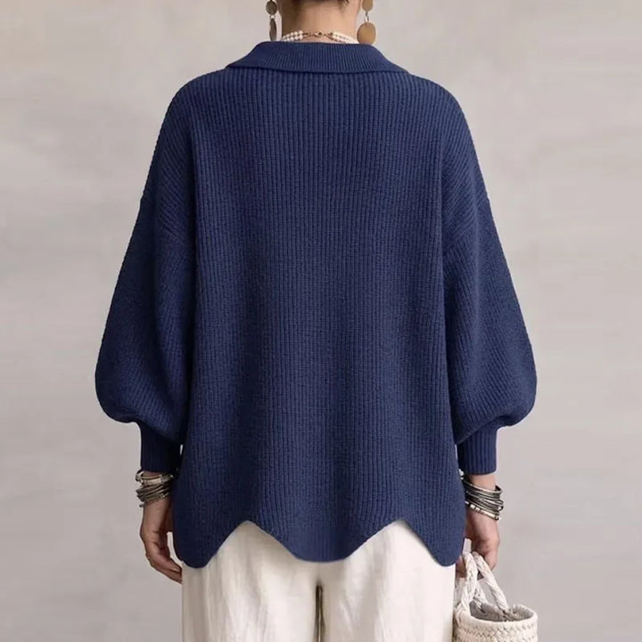 Woman wearing a navy blue ribbed knit cardigan with puffed sleeves and a unique scalloped hem, seen from the back.