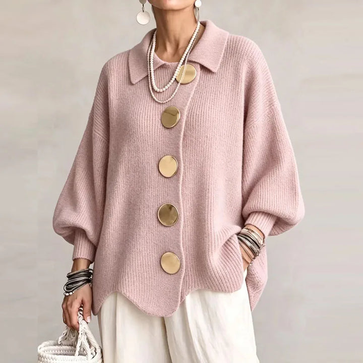 Woman wearing a pink knitted cardigan with a large collar, oversized sleeves, and four prominent gold round buttons.