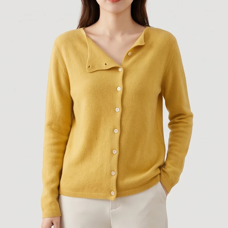 Woman wearing a yellow knitted cardigan with an asymmetrical V-neckline and cream-colored buttons, her hand in a pocket.