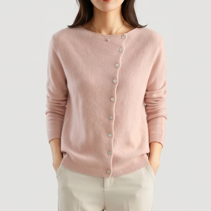 Woman wearing a soft pink knit cardigan with a boat neck and a diagonal light gray button placket.
