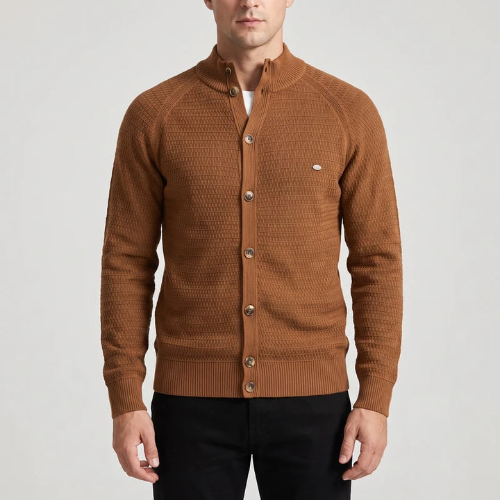 Man wearing a brown knit cardigan with a stand-up collar, front buttons, and subtle textured pattern over a white t-shirt.