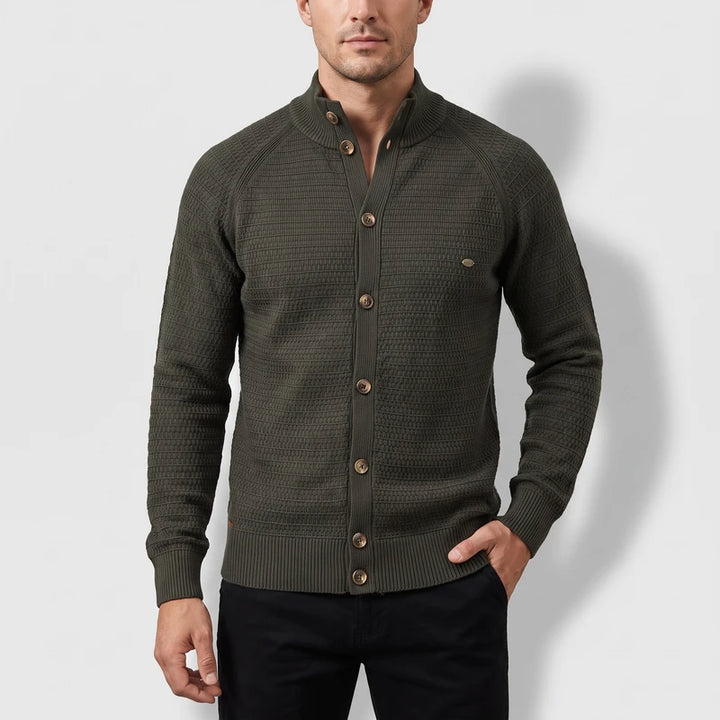 Man wearing a dark olive green knit cardigan with a stand-up collar, wooden buttons, and subtle textured pattern.