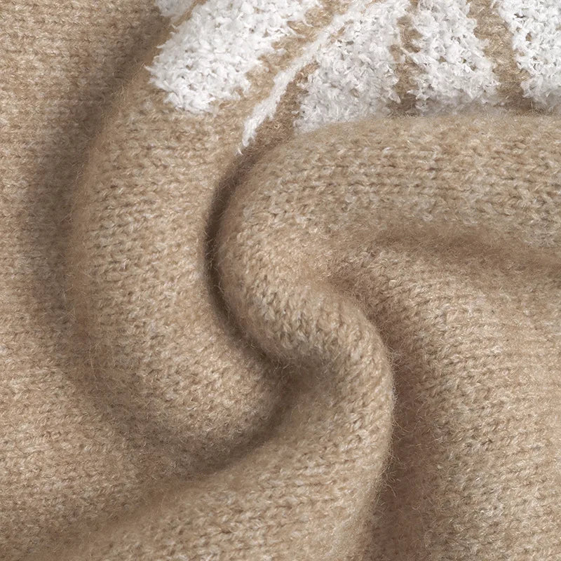 Close-up of a soft, fuzzy beige knit fabric with a textured white daisy petal design in the upper right corner.