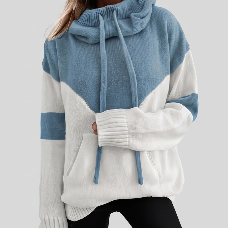 Woman wearing a two-tone knit hoodie with a blue top, white chevron pattern, front pocket, and matching drawstrings.