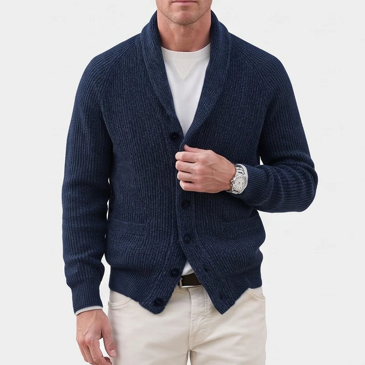 Man wearing a dark navy blue ribbed knit cardigan with a shawl collar, layered over a white t-shirt.