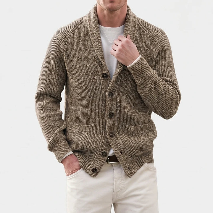 Man wearing a textured, ribbed brown knit cardigan with a shawl collar, dark buttons, and two front pockets.