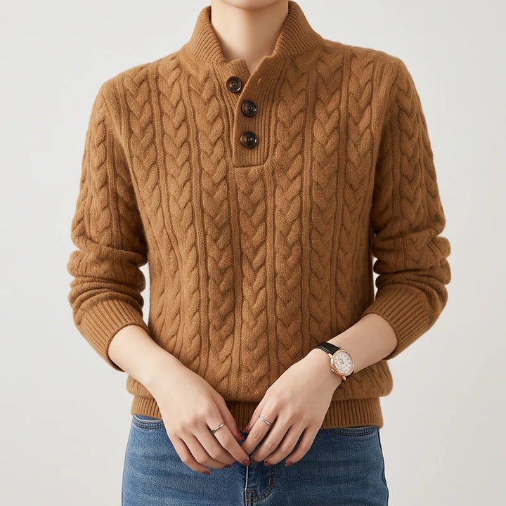 Woman wearing a brown cable-knit sweater with a high collar and three dark buttons, paired with blue jeans.