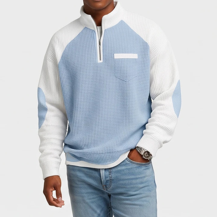 Man wearing a light blue and white waffle knit quarter-zip pullover sweater with a chest pocket and raglan sleeves.