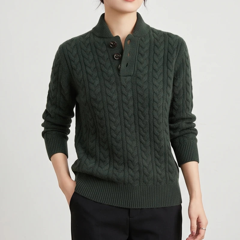 Woman wearing a dark green cable knit sweater with a stand collar and three dark brown buttons on the placket.