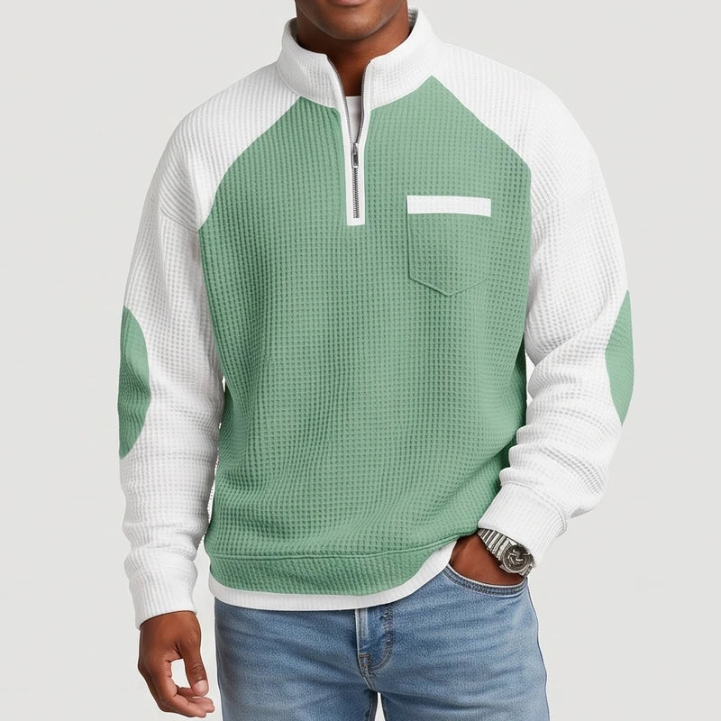 Man wearing a two-tone waffle knit half-zip sweater with white raglan sleeves, green elbow patches, and a chest pocket.