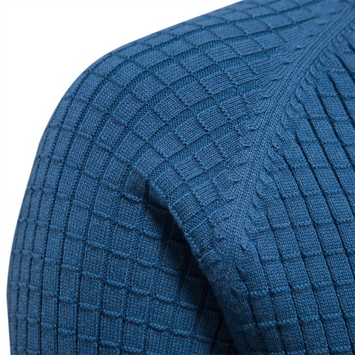Close-up of a blue knit sweater with a textured basketweave pattern on the shoulder and ribbed sleeves.