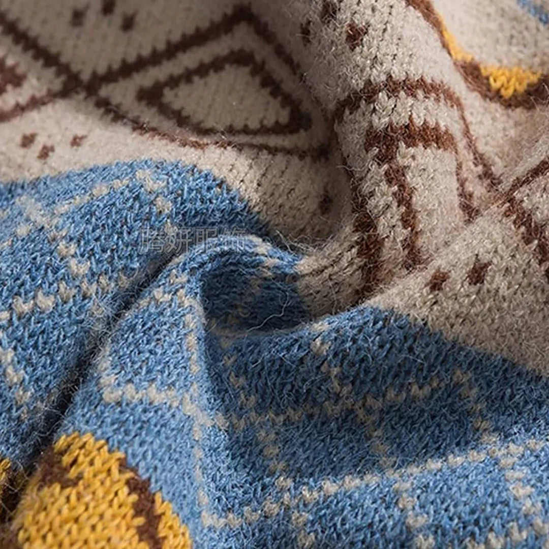 Close-up of a chunky knit sweater in blue, cream, yellow, and brown, featuring an intricate geometric pattern.