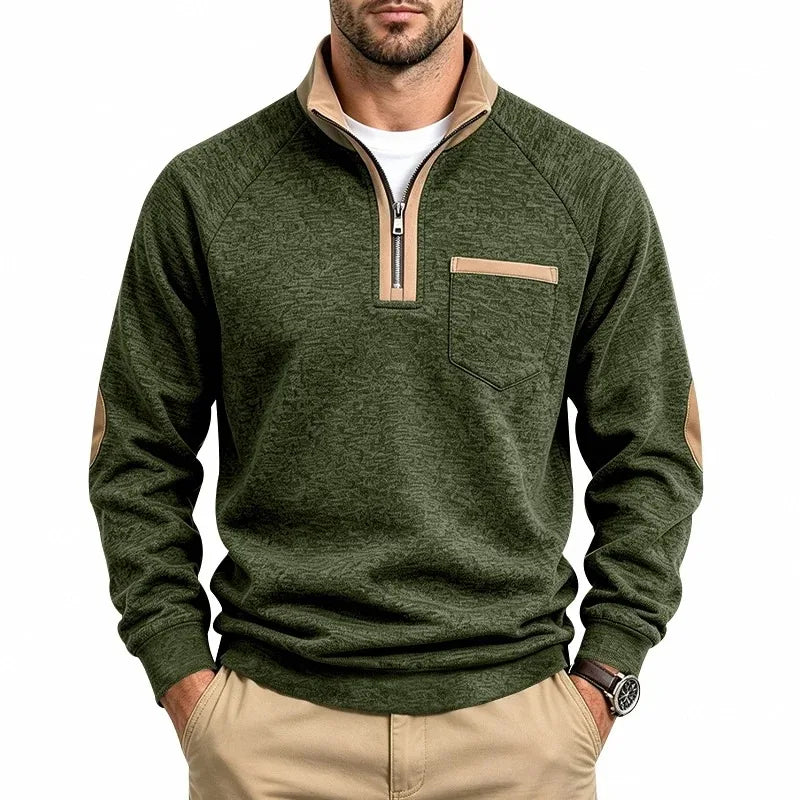 Man wearing a textured green knit half-zip sweatshirt with a tan collar, chest pocket, and elbow patches.