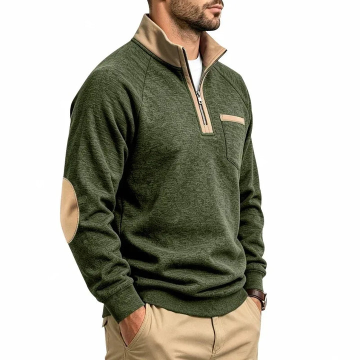 Man wearing a mottled green knit quarter-zip sweatshirt with a tan collar, elbow patches, and chest pocket.